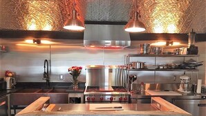 A modern kitchen with stainless steel appliances, a central island, pendant lighting, and a textured wall. - Sea Street Inn (Hyannis)