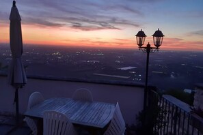 A table and chairs on a terrace overlooking a cityscape at sunset. - Apartment with pool use, terrace, historical centre, for family (sermoneta)