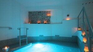 Ein Wellnessbereich mit Whirlpool, Steinwand und kleinem Fenster.
