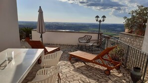 Eine Terrasse mit Tisch, Stühlen und einer Liege.