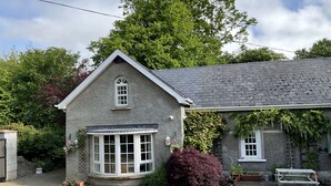 A stone cottage with a gabled roof, a bay window, and a small porch.