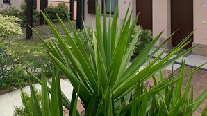 A building with a light pink facade, wooden pergola, and a garden with green plants. - La Quiete 56 Holideal Apartment (Tremosine)