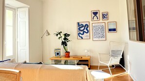 A room with a bed, a chair, a table with a plant, and artwork on the wall. - Charming Graça - 4 pax (Lisboa)