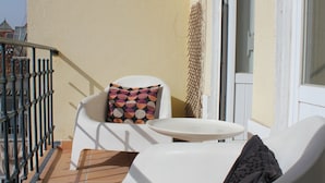 A balcony with a white chair, a small round table, and a patterned cushion. - Charming Graça - 4 pax (Lisboa)