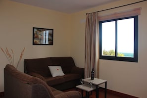 Un salón con sofá, una mesita y una ventana con vistas.