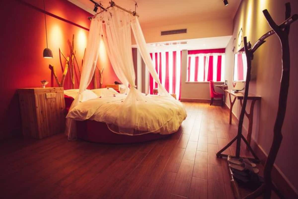 Une chambre à coucher avec un lit à baldaquin, un plancher en bois, une table de chevet et une chaise.