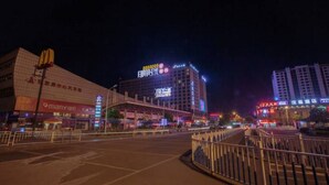 Een stadsgezicht bij nacht met verlichte gebouwen, waaronder een opvallend hotel met een grote reclame en een casino.
