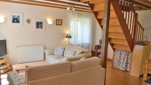 Ein gemütliches Wohnzimmer mit einer Couch, einem Fernseher und einer Treppe.