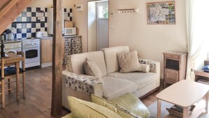Ein gemütliches Wohnzimmer mit einer Couch, einem Tisch und einer Küchenzeile mit Herd und Mikrowelle.