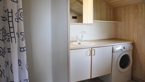 Un baño pequeño y limpio con lavamanos, espejo y lavadora.