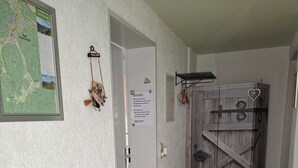 En hall med en karta, en välkomstskylt, en trädörr och en dörrmatta.
