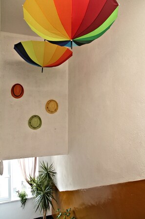 Teto decorado com um guarda-chuva colorido, três chapéus e um vaso de planta.