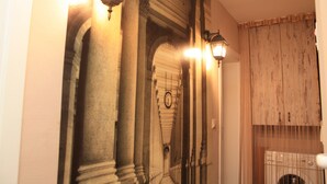 Ein Korridor mit klassischer Architektur, darunter Säulen und Bögen, und einer Uhr an der Wand.