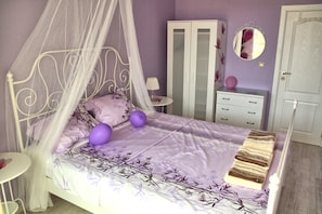 A bedroom with a four-poster bed, a wardrobe, a bedside table, and a mirror on the wall.