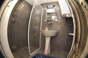 A bathroom with a shower, a sink, a mirror, and a toilet.