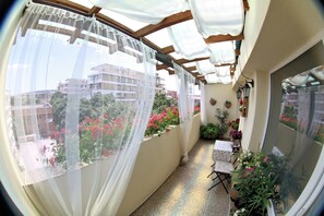 A narrow balcony with a view of buildings and flowers. - Vintage apartment in the city jungle (Varna)