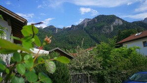 A residential area with houses, a wooden fence, and a mountain backdrop. - Ferienwohnung II° "Bergstüberl" mit extra Schlafzimmer und Balkon, 60 qm (Aschau im Chiemgau)