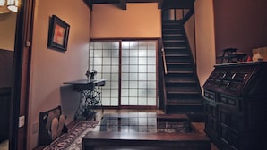 Una habitación japonesa tradicional con suelo de tatami, puerta corrediza de shoji, escalera de madera y una máquina de coser.