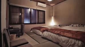 Habitación de hotel con cama, una silla, una mesita, lámpara y ventana con vistas.