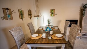 Ein Esszimmer mit einem Holztisch, gedeckt für vier Personen, umgeben von Korbstühlen.
