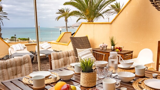 Ein Essbereich mit gedecktem Tisch für das Frühstück, mit Blick auf das Meer.