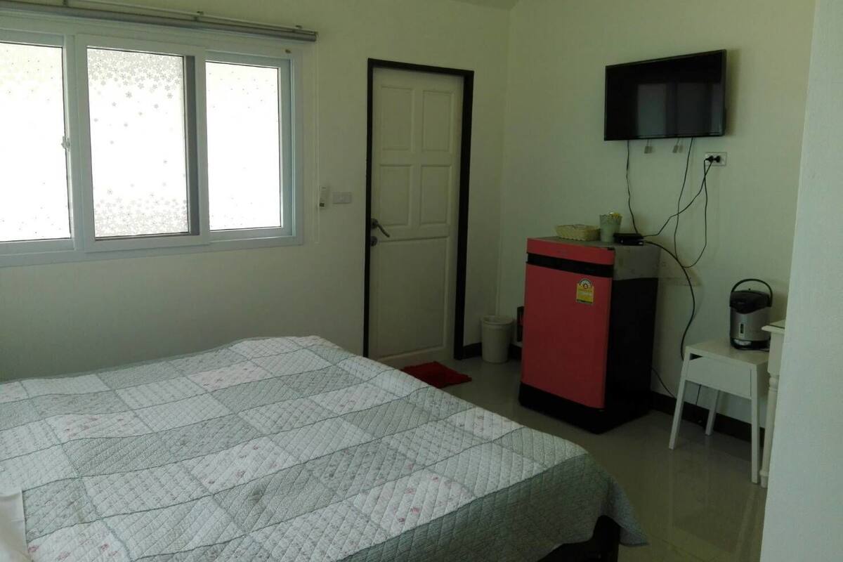 Un dormitorio con una cama, un escritorio, un televisor y un refrigerador.