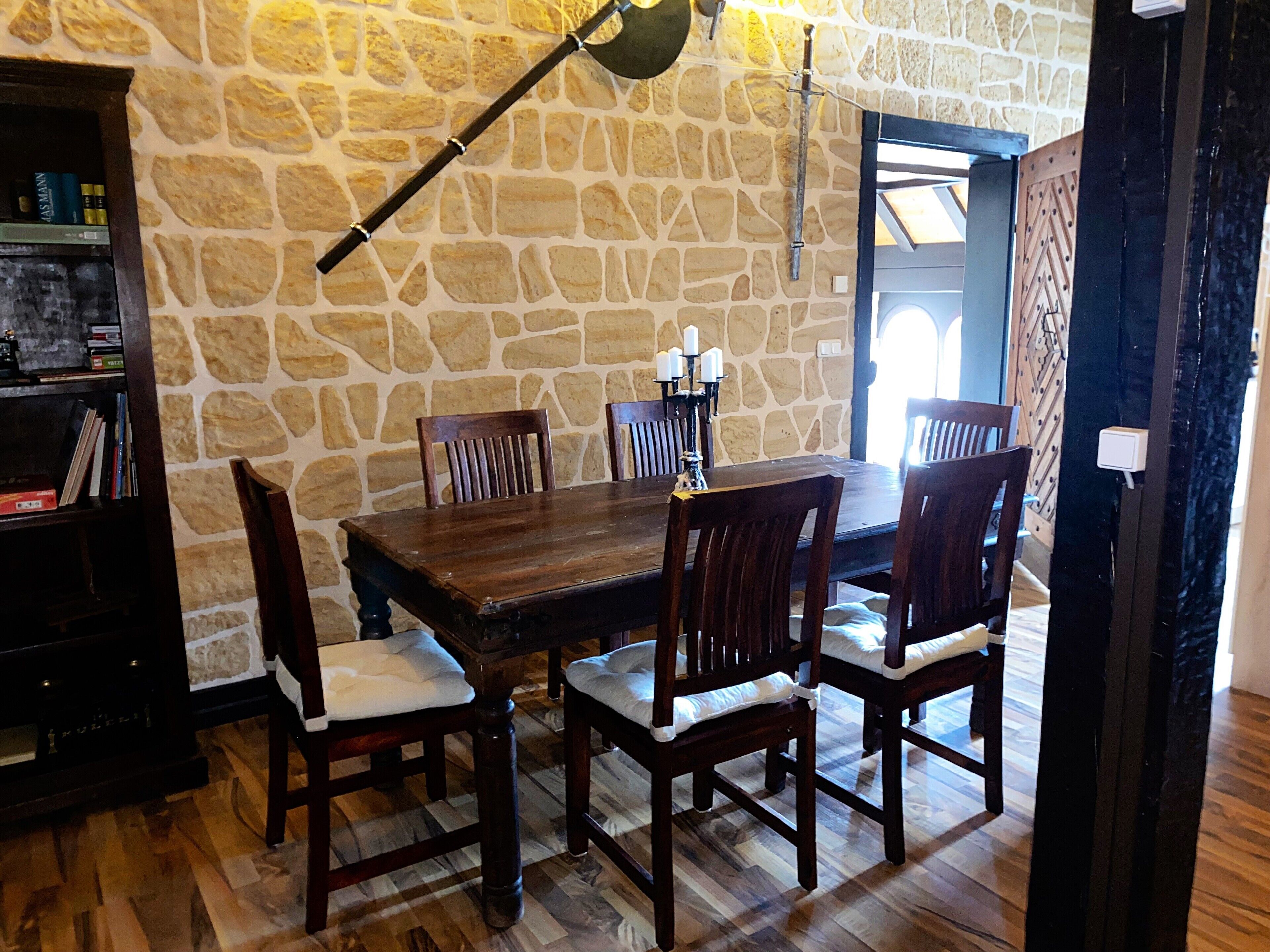 Un comedor con pared de piedra, mesa de madera y sillas.