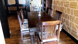 A dining area with a wooden table and chairs, stone walls, and a brick fireplace.