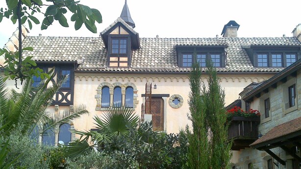 A traditional building with a tiled roof, multiple windows, and a garden with various plants.