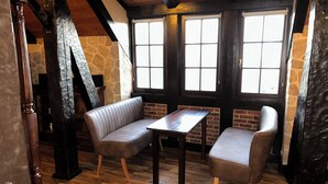A cozy room with a stone wall, wooden beams, a bench, and a table.