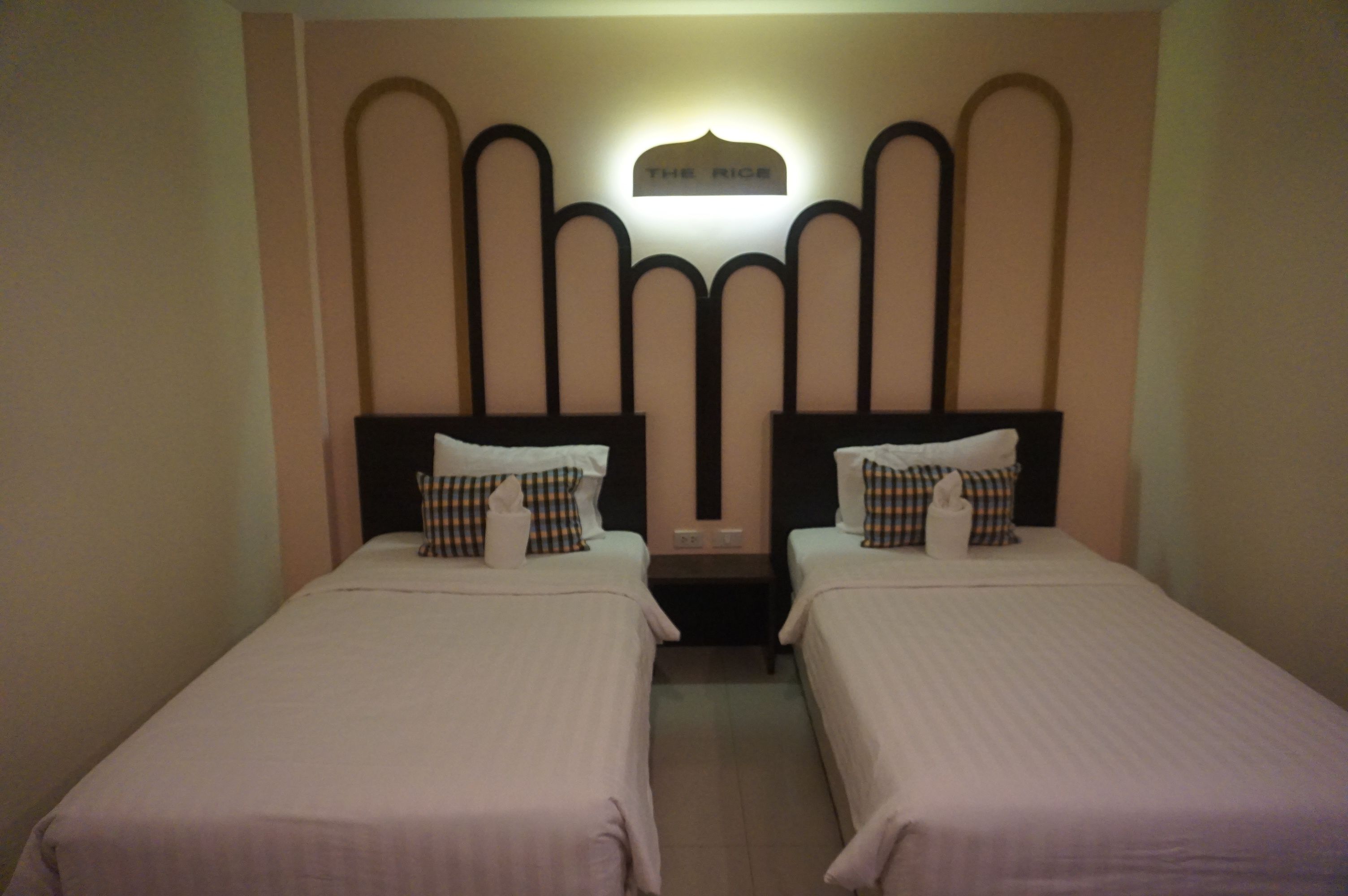Two single beds with headboards, a nightstand, and a wall-mounted light fixture.