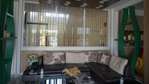 Una sala de estar moderna con un sofá de cuero negro, una mesa de centro de vidrio y un separador decorativo con listones verticales.