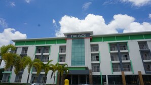 Un hotel de varios pisos llamado "The Rice" con fachada verde y blanca, múltiples balcones y un cielo despejado con nubes.