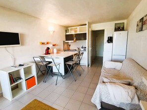 A compact living space with a kitchenette, a dining area, and a sofa.