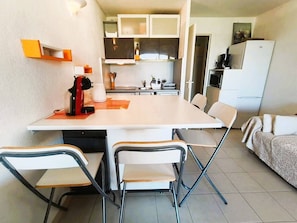 Uma cozinha compacta com mesa, cadeiras e geladeira.
