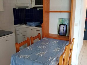 Uma cozinha compacta com micro-ondas, fogão e toalha de mesa estampada em azul.