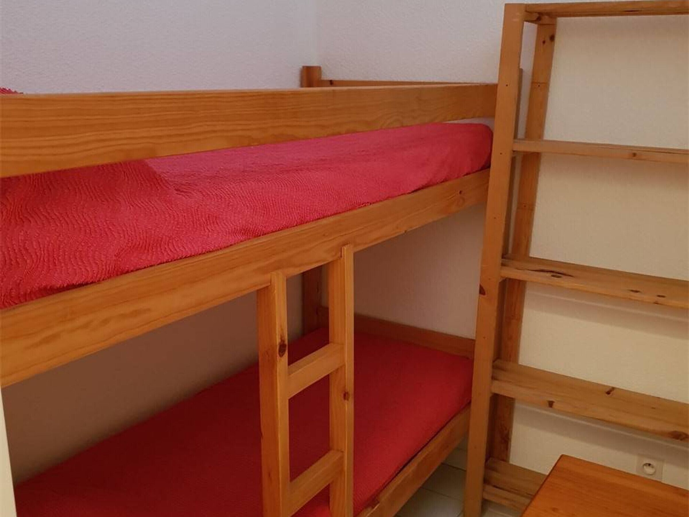 Una litera con colchón rojo y estructura de madera.