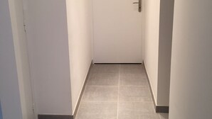 Un corridoio stretto con una porta chiusa in fondo.