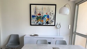 Zona pranzo moderna con un tavolo rettangolare, sedie grigie, un mobile bianco e un quadro appeso al muro.