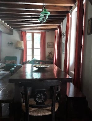 A dining area with a wooden table, chairs, and a hanging light fixture. - OFFRE 2025 - Superb house (former 18th century mill) entirely renovated (Adon)