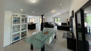 A modern kitchen with a glass dining table, white cabinets, and a black stove. - Superb farmhouse in a beautiful green setting, breathtaking view of the Canigou  (Vivès)