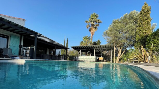 A swimming pool with lounge chairs and a covered area, surrounded by trees and a building with a green door. - Superb farmhouse in a beautiful green setting, breathtaking view of the Canigou  (Vivès)