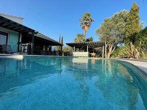A swimming pool with lounge chairs and a covered area, surrounded by trees and a building with a green door. - Superb farmhouse in a beautiful green setting, breathtaking view of the Canigou (Vivès)