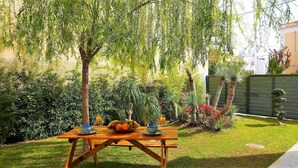 A wooden picnic table with a bowl of fruit and a glass of orange juice. - 30villa Rd in Rhodes (Rodos)