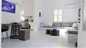 A modern living space with a dining area, a grey sofa, and a black chair. - 30villa Rd in Rhodes (Rodos)