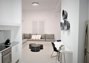 A modern kitchen with a built-in oven, a dining area with a white table and black chairs, and a grey sofa with cushions. - 30villa Rd in Rhodes (Rodos)