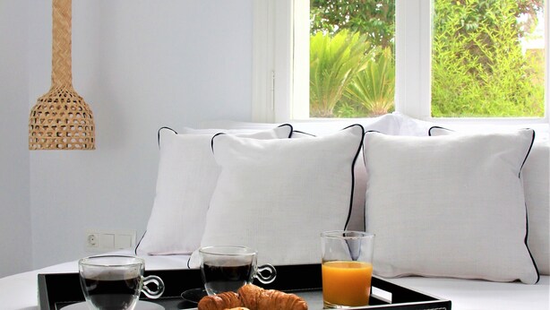 A neatly made bed with a tray of breakfast items including croissants, coffee, and orange juice. - 30villa Rd in Rhodes (Rodos)
