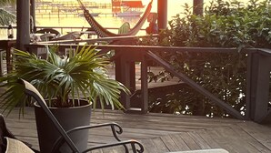 Eine Holzterrasse mit Liegestühlen und einer Hängematte mit Blick auf einen Sonnenuntergang.