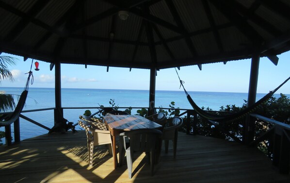 Relax in a serene outdoor setting with a table and chairs overlooking the sea.