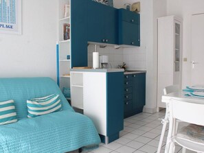 A room with a teal bed, a kitchenette with blue cabinets, and a white door. - 2-room apt for 4 in Châtelaillon-Plage, pool available (Châtelaillon-Plage)